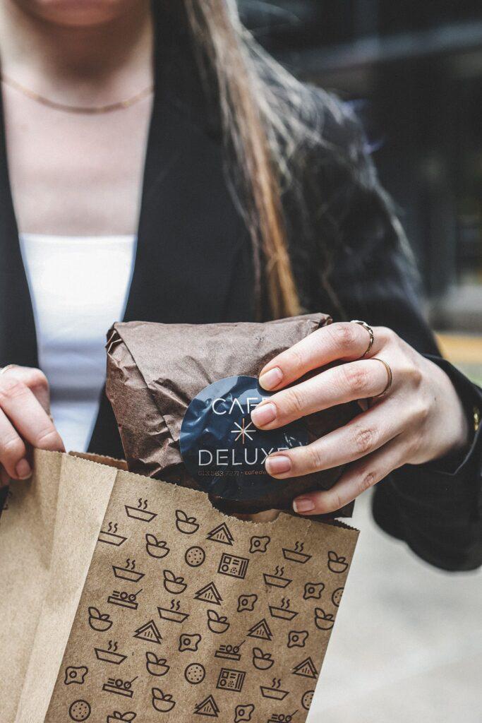 A customer takes a sandwich from her bag